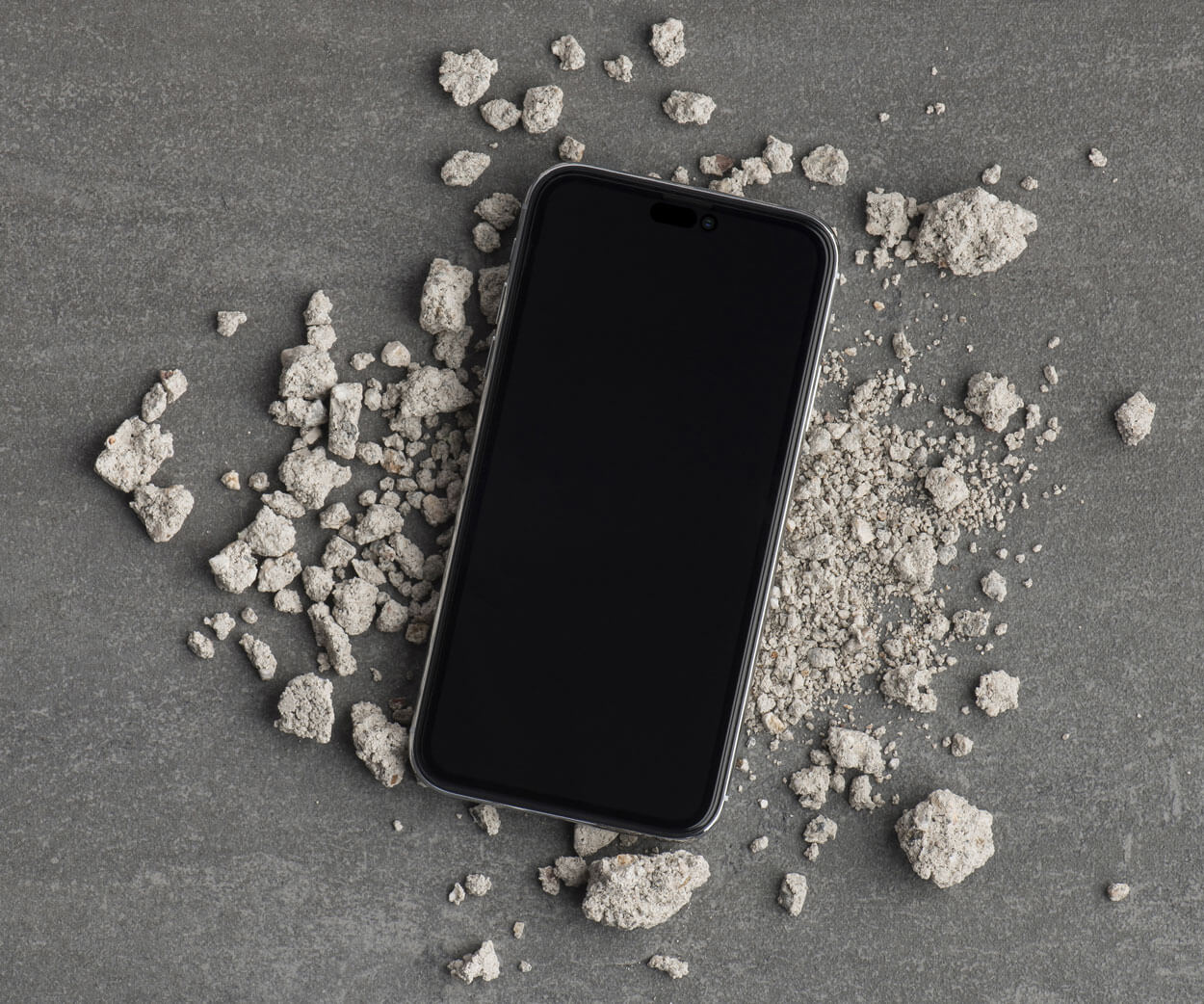 an iPhone 16 pro with a screen protector surrounded by small rocks and pebbles