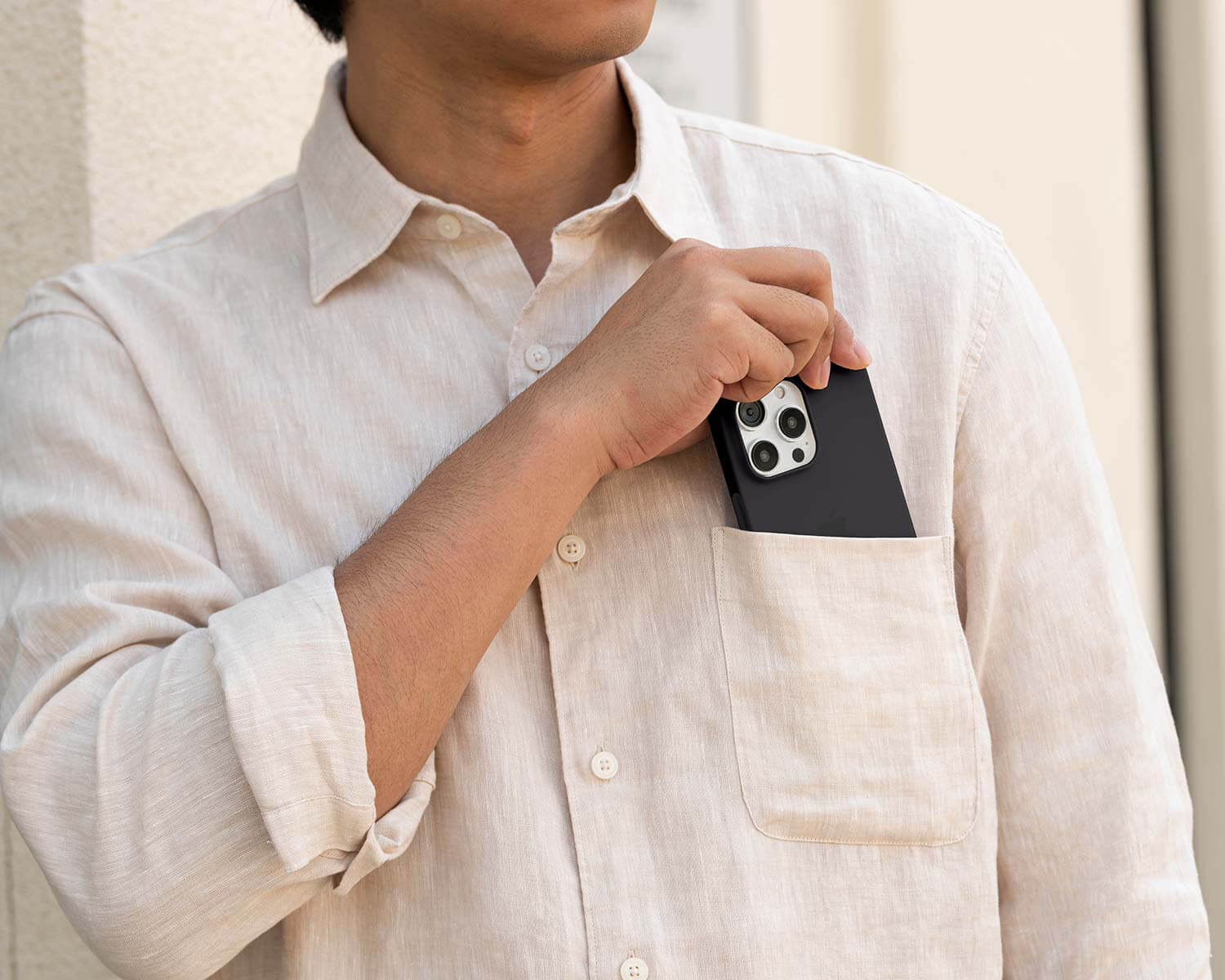 a man removing a black iPhone 16 Pro Max from his chest pocket